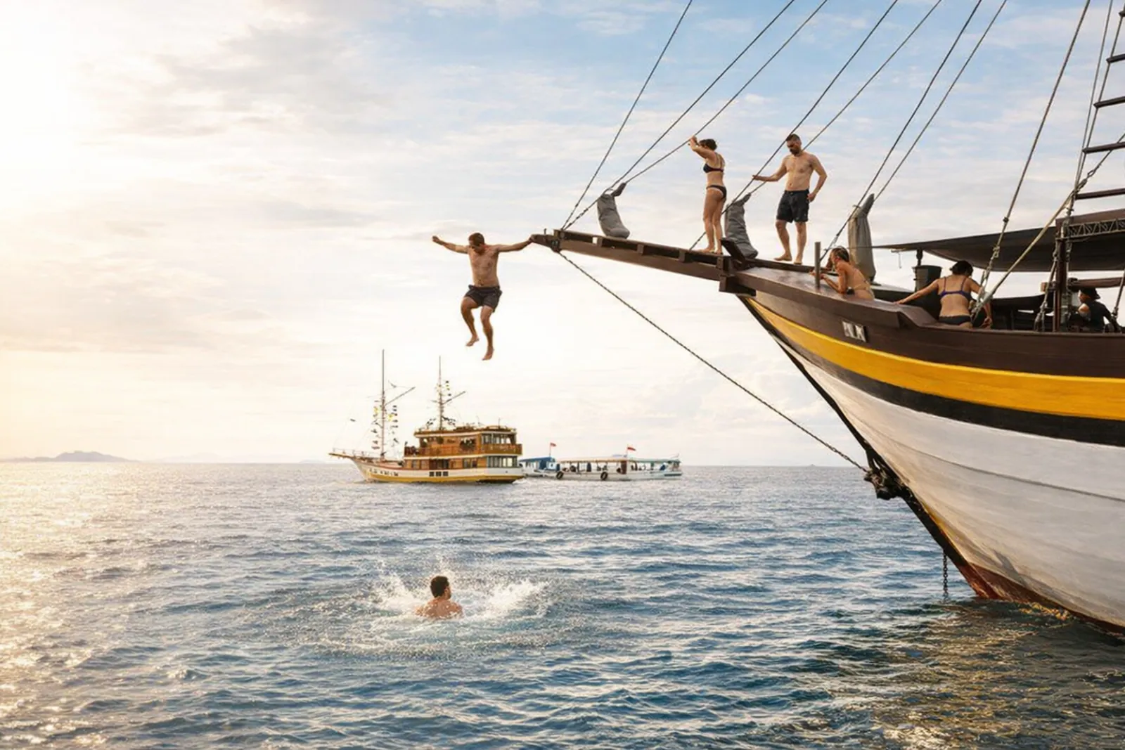 Guests jumping from the bowsprit of a Komodo liveaboard into the sea