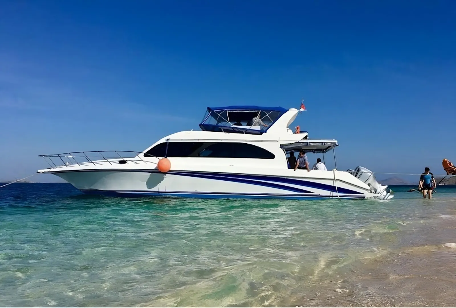 Tour speedboat drawn up in shallow turquoise water at a beach stop