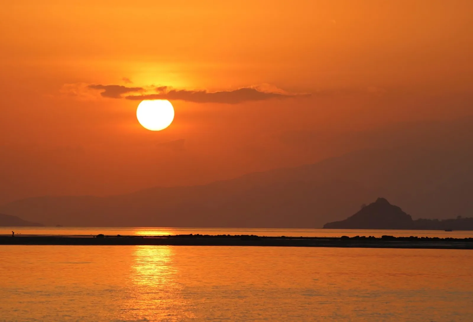 The sun dropping to the horizon over the sea off Labuan Bajo