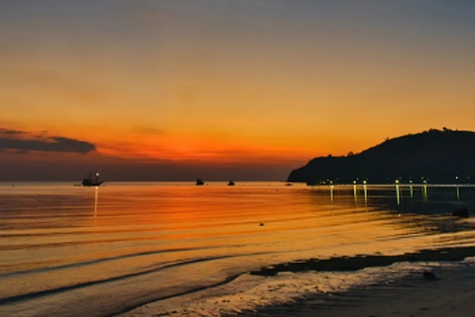 Boats silhouetted on the water at sunset off the Flores shoreline