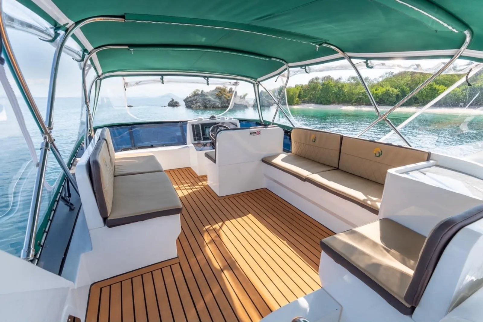 Shaded teak lounge deck of a Komodo tour speedboat under a green canopy