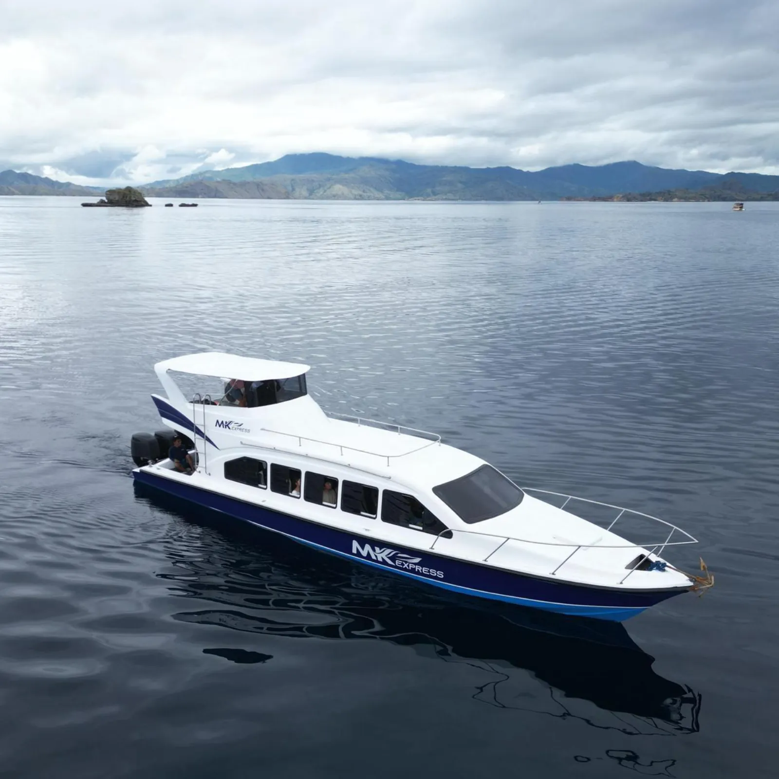 The shared tour boat on flat water under an overcast Komodo sky
